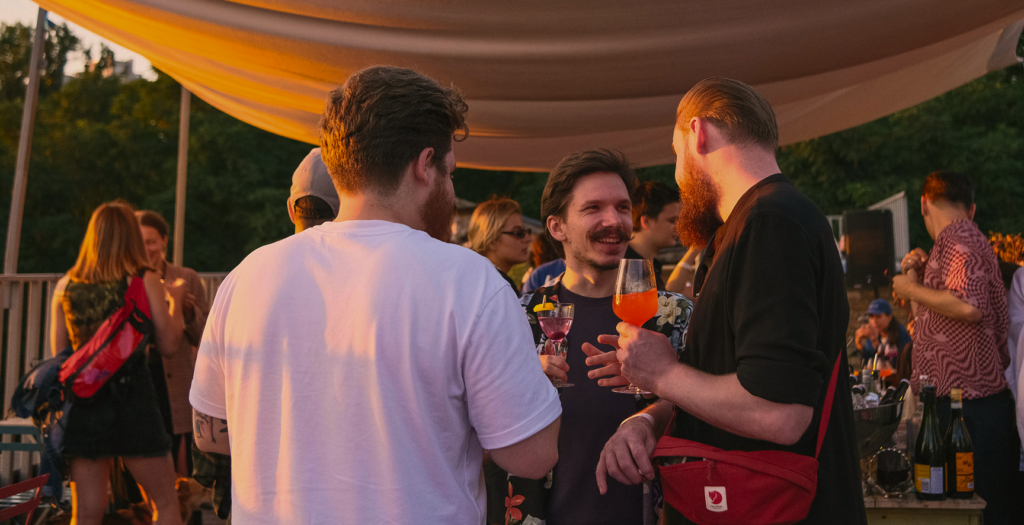 Nous sommes dans une fête, avec plusieurs personnes. Il apprennent à se connaître, dans un moment conviviale & chaleureux. L'image a des teintes chaudes.