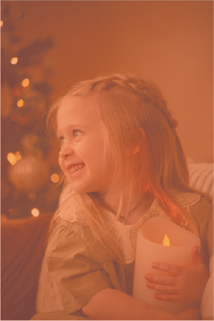 Une petite fille tenant une bougie et elle sourit, elle est heureuse