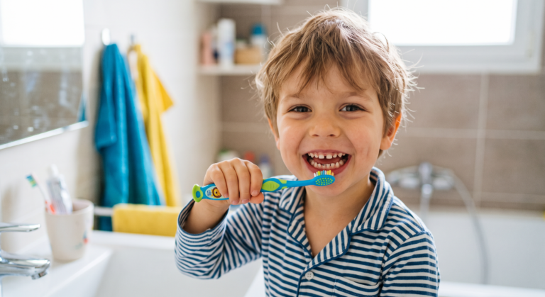 Un enfant qui se brosse les dents dans la salle de bain.